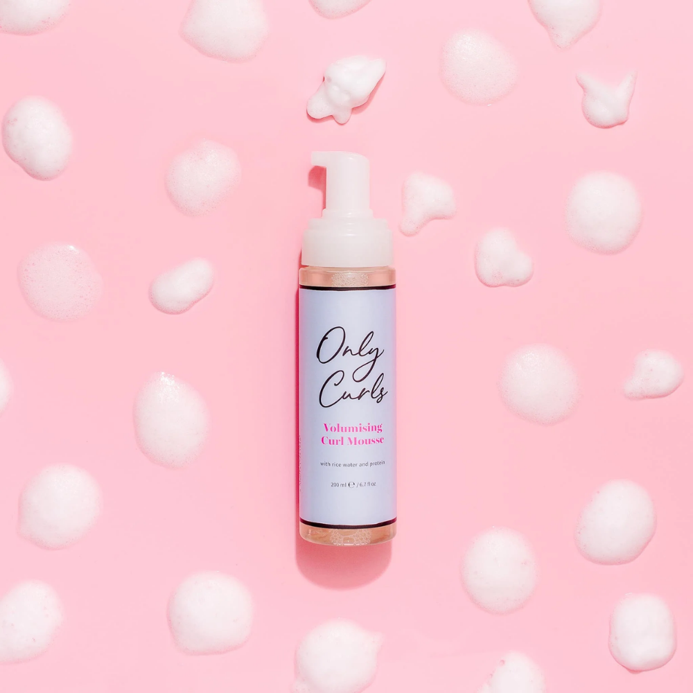Only Curls Volumising Curl Mousse omringt met allemaal dotjes van de mousse als sfeerfoto