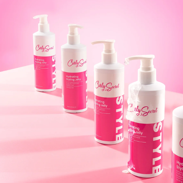 Een rij van Curly Secret Hydrating Styling Jelly in een roze studio