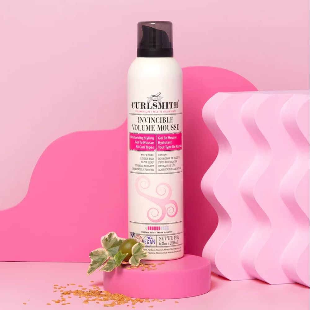 Curlsmith Invincible Volume Mousse in sfeeromgeving met roze achtergrond