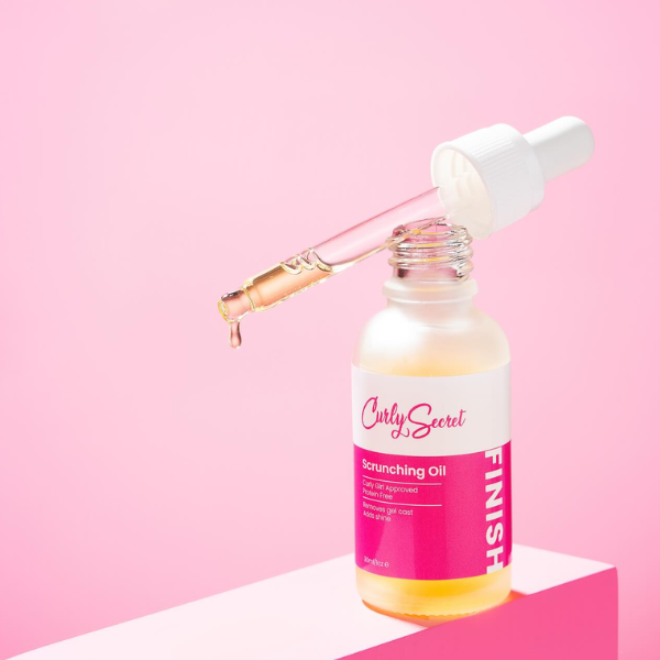 Curly Secret Olie in sfeeromgeving met een drupje olie dat uit de pipet komt.