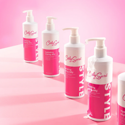 Een rij van Curly Secret Hydrating Styling Jelly in een roze studio