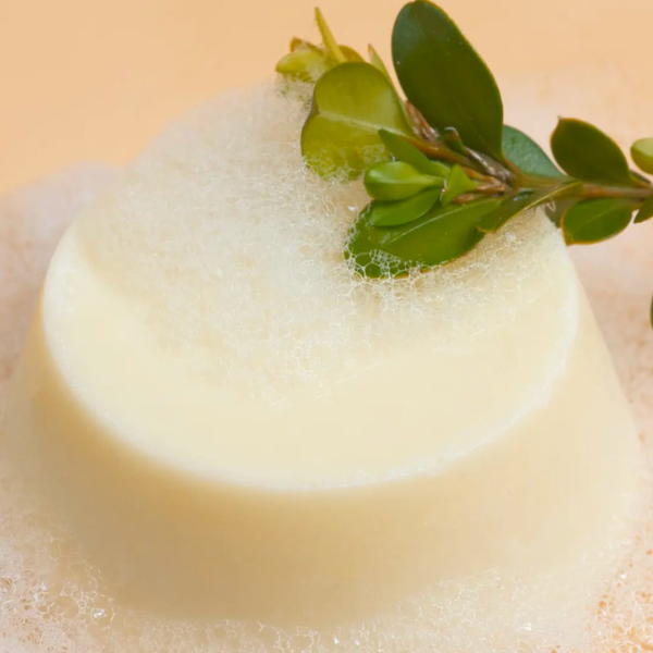 De gele conditioner bar uit verpakking met schuim en water van Curly Secret